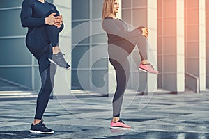Young fitness couple in a sportswear, doing stretching in the modern city against a skyscraper. Healthy lifestyle