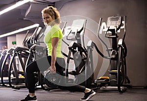 Young fitness girl doing lunges for legs with iron plates in her hands