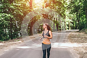 Young fitness girl running and listening music in the park