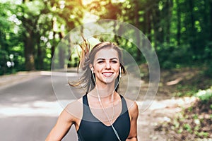 Young fitness girl running and listening music in the park