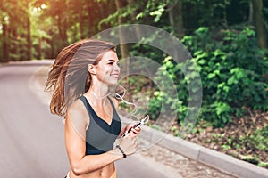 Young fitness girl running and listening music in the park