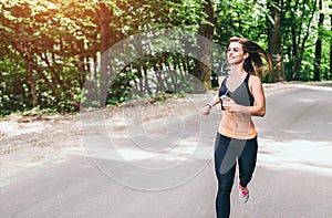 Young fitness girl running and listening music in the park