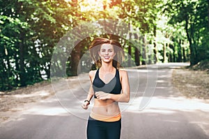 Young fitness girl running and listening music in the park