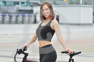 Young fitness girl with sport bike is walking in the city