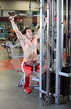 Young fitness guy working out on exercise machine