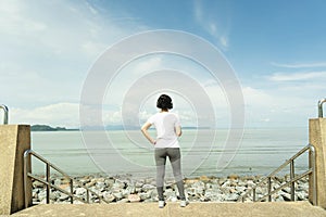 Young fitness healthy woman stand and rest listening to music on headphones after before running or jogging in the beach in