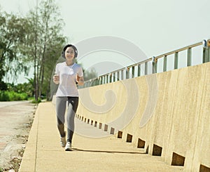 Young fitness healthy woman stand and rest listening to music on headphones after before running or jogging in the beach in
