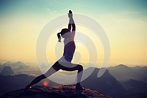 Fitness woman meditating on sunrise mountain peak