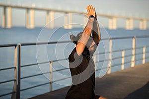 Young fitness man in activewear practices yoga at seaside outdoors