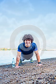 Young fitness man doing push-ups outdoors