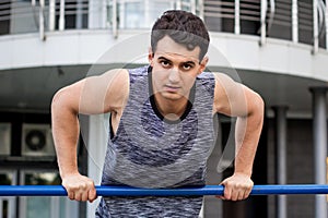 Young fitness man exercises on horizontal bar during training workout