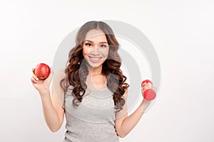 Young fitness model woman athlete in sportswear with red dumbbell and green apple. Healthy life bodybuilding lifestyle concept