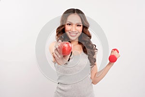 Young fitness model woman athlete in sportswear with red dumbbell and green apple. Healthy life bodybuilding lifestyle concept