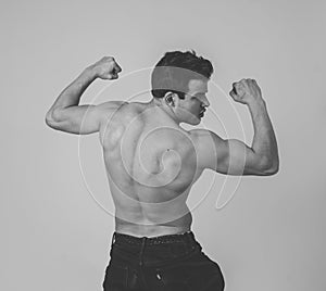 Young fitness muscly man showing his back,shoulders, triceps and biceps muscles after training