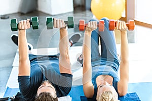 Young fitness people exercising with dumbbells at fitness studio