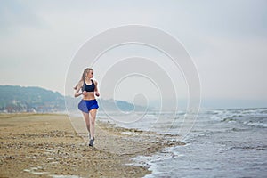 Young fitness running woman jogging on beach