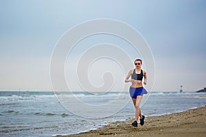 Young fitness running woman jogging on beach