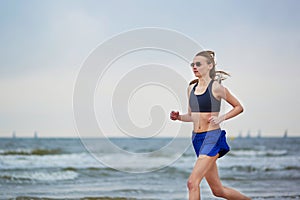 Young fitness running woman jogging on beach