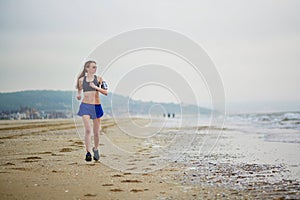 Young fitness running woman jogging on beach