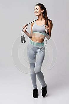 Young fitness sportive girl posing smiling holding jumping rope over white background.
