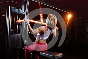 Young fitness woman doing exercises the major muscle groups in the gym. Strength training. Fiery training machine.