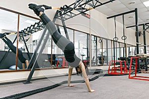 Young fitness woman doing exercises using the straps system in the gym. Sport, fitness, training, people concept