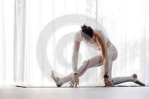 Young fitness woman doing stretching on her yoga training