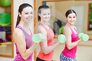 Young fitness woman with dumbbell in gym