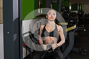 young fitness woman execute exercise with exercise-machine Cable Crossover in gym, horizontal photo