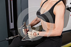 young fitness woman execute exercise with exercise-machine Cable Crossover in gym, horizontal photo