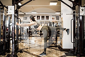 Young fitness woman execute exercise with exercise-machine Cable Crossover in gym