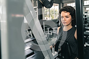 Young fitness woman execute exercise with exercise-machine in gym