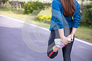 Young fitness woman exercising in sunny bright light in the morning at public park before running