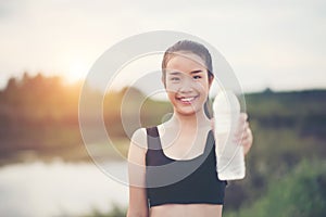 Young fitness woman hand holding water bottle after running