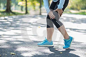 Young fitness woman holding his sports leg injury, muscle painful during training. Asian runner having calf ache and problem after