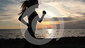 Young fitness woman jogging on seaside at sunset