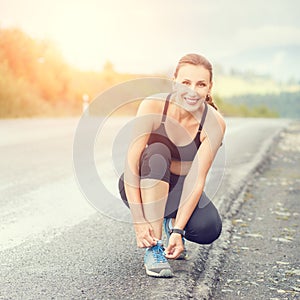 Young fitness woman lace up her trainers before jog