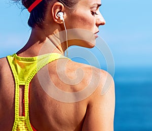 Young fitness woman listening to music at embankment