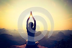 Woman meditating on sunrise mountain peak