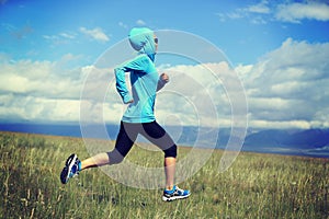 Young fitness woman runner running on beautiful trail in grassland