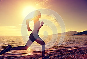Young fitness woman runner running on sunrise seaside
