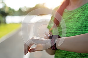 Young fitness woman runner setting up smart watch before running training during sunset. Outdoor exercise activities concept
