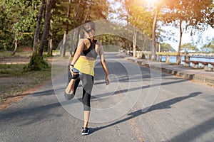 Young fitness woman runner stretching legs before run on city, Young fitness sport woman running on the road in the morning photo