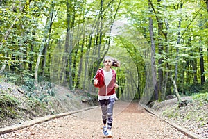 Young fitness woman running at forest trail