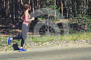 Young fitness woman running on forest trail. Runner athlete jogging workout wellness concept