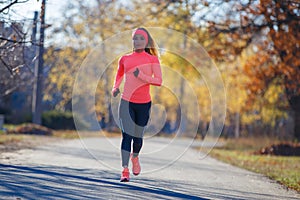 Young fitness woman running on the road in the cold morning in winter.