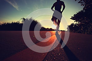 Young fitness woman running on sunrise seaside trail