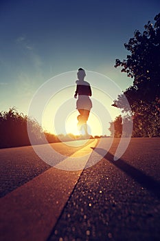 Young fitness woman running on sunrise seaside trail