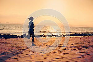 Young fitness woman running at sunset beach