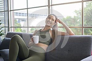 Young fitness woman in sportswear having a cup of coffee after exercising at home, Healthy and Lifestyles
